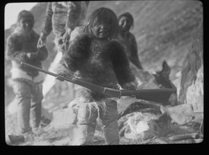 Image of Four Inuit. Girl with rifle